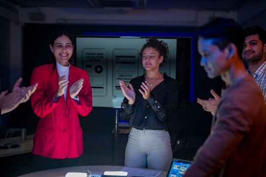 Creative UI/UX design team analyzing mobile app wireframes on illuminated digital touch table. Diverse developers brainstorming web layout strategy in modern high-tech office at night. - Powered by Adobe
