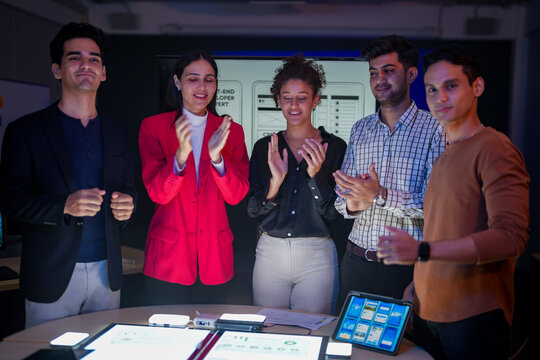Professional software development team applauding for project success. Happy diverse group clapping hands to celebrate mobile app launch in high-tech startup office. - Powered by Adobe