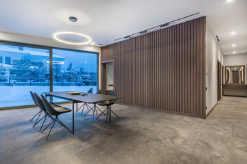 The interior of a spacious living room of a private house with a table and chairs. It's twilight...