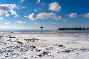 frozen bay of Lake Constance in Wasserburg Germany with blue sky and clouds