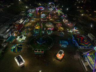 Aerial view of the vibrant fairground glows with a myriad of colorful lights, casting a warm, inviting glow against the dark night sky, Nassau, Bahamas.