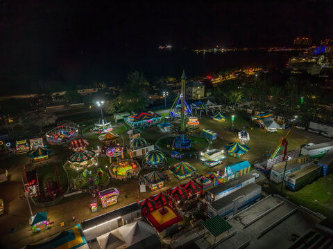 Aerial view of a brightly lit carnival ground with spinning rides and colorful tents under the dark night sky, Nassau, Bahamas.