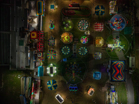 Aerial view of an illuminated fairground unfolds with a tapestry of vibrant rides and structures, painting the night with playful colors, Nassau, Bahamas.