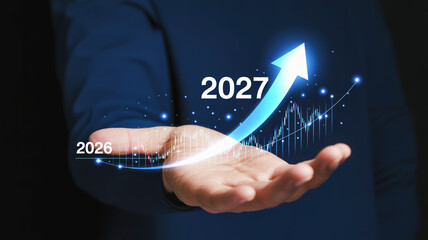 Hand holding glowing digital graph with upward arrow and year 2027 business growth