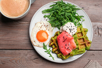 Healthy breakfast with green spinach waffles, salmon, cream cheese, fried egg and salad