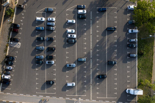 Aerial view of a parking lot filled with cars, neatly arranged in rows under the soft sunlight, contrasting against the dark asphalt, Dresden, Saxony, Germany.