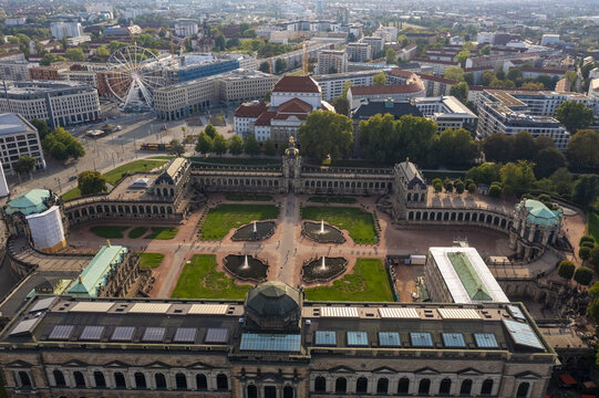 Aerial view of Zwinger Palace's baroque architecture and manicured gardens contrasts with the modern cityscape beyond, a tapestry of history and progress, Dresden, Saxony, Germany.
