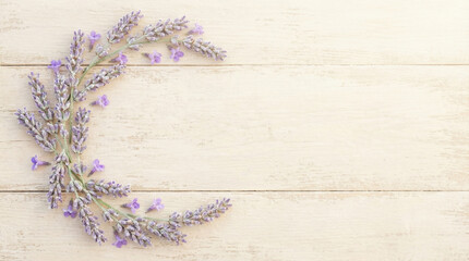 Lavender wreath arranged in a crescent shape on wooden background  
