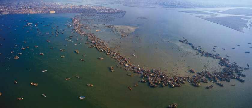 Aerial view of numerous boats congregating along the river's edge near Prayagraj, creating a dense aquatic gathering, Prayagraj, Uttar Pradesh, India.