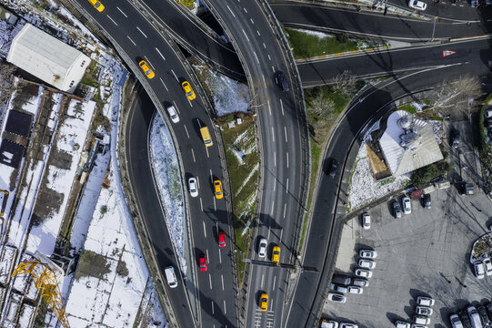 Aerial view of roads intertwine like ribbons above snow-dusted buildings, revealing the pulse of urban life amidst muted winter hues, Istanbul, Istanbul, Turkey.