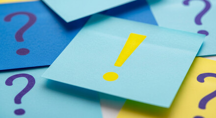 Close-up of paper notes. Yellow exclamation point and purple question mark on blue, yellow paper, symbolizing a question, answer, decision