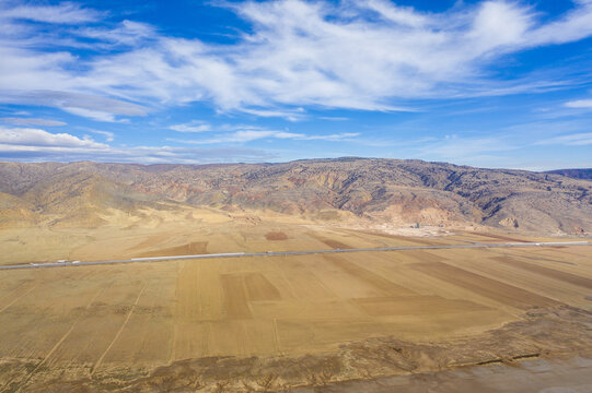 Aerial view of vast fields meeting rugged mountains under a sky streaked with wispy clouds, a serene landscape of earth and sky harmonizing, saray/van, Turkey.