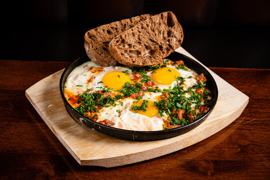 Delicious shakshouka features poached eggs nestled in a spicy tomato sauce, complemented by bread