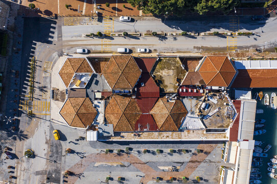Aerial view of the colorful, hexagonal rooftops of a market building stand in contrast to the azure harbor waters, Kusadasi, Aydin, Turkey.