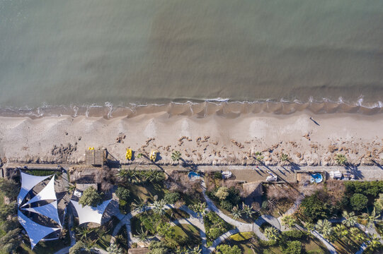 Aerial view of silver beach with its golden sands meeting the gentle waves of the sea, and a pier stretching out into the water, Kusadasi, Aydin, Turkey.