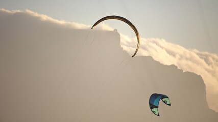 Aerial view of kites dancing against a backdrop of billowing clouds kissed by the golden light of dusk, Cape Town, Western Cape, South Africa.