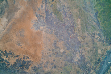 Abstract ground texture with mud runoff and dry grass, geological erosion background, aerial drone shot top view, alluvial fan and dendritic pattern