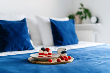 Cozy hotel bedroom with dessert on a wooden tray and blue bedspread