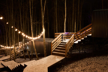 Decorative stairway with string lights into snowy forest path