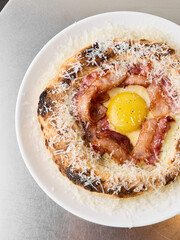 Food styled breakfast pizza with egg yolks and bacon strips