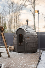 Textured shingles and snow surround warm sauna entrance emitting steam
