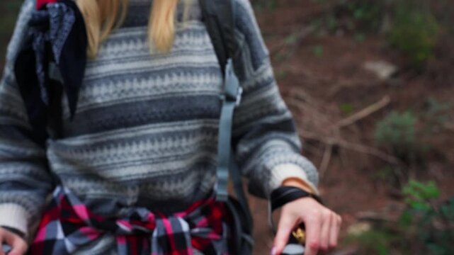 Female hiker using gold compass to navigate way through forest while carrying backpack. Represents themes of journey, discovery, and outdoor exploration. Outdoor adventure concept