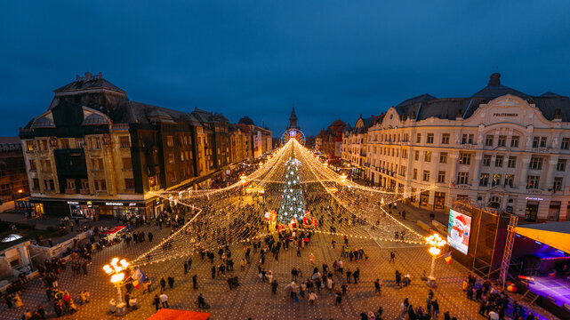 Aerial view of Christmas lights twinkling like stars over a bustling square, illuminating the historic buildings around Piata Victoriei, Timisoara, Timis, Romania.