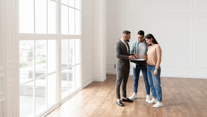 Consultation With Expert. Smiling young couple discussing contract details making agreement with...