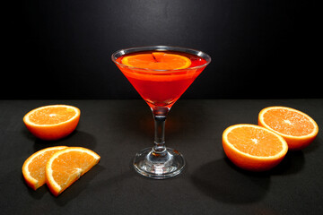 Vibrant orange cocktail juice glass with fresh citrus on black background closeup view