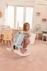 Toddler baby playing on the rocking bike in the kindergarten