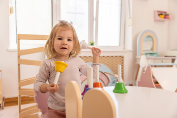 Happy toddler girl playing with bells in the kindergarten