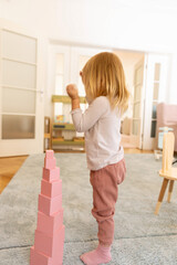 Small girl playing with wooden cubes in the kindergarten