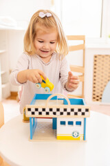 Little girl playing with small wooden car in the kindergarten