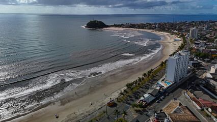 Drone footage of the coastal city of Guaratuba, Paran&aacute;, on a sunny morning, blending the blue sky with clouds, the beach, and the city.