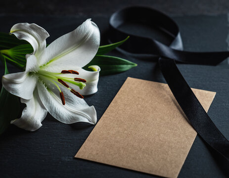 Wei&szlig;e Lilie mit Kondolenzkarte und Trauerband &ndash; stilles Beileid