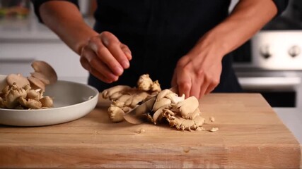 Hands of a chef using a sharp knife to dice mushrooms on a rustic wooden cutting board.