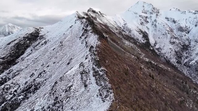 Stunning aerial view of a rugged mountain top covered in patches of snow and bare rocky earth.