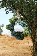 Rustic paper decorations hanging from tree branch in countryside outdoor setting