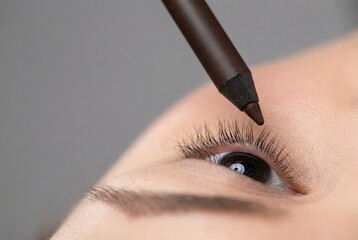 Applying eyeliner to enhance eyes during makeup routine in a close-up setting