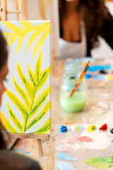 Women painting tropical leaves during art workshop