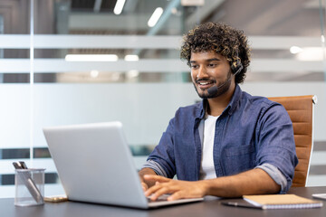 Young Indian man in headset working focused in office at laptop