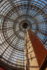 Photograph of the historic Coop's Shot Tower in Melbourne, Australia, encased under a massive modern glass dome at Melbourne Central Shopping Centre. A stunning contrast of old-world architecture 