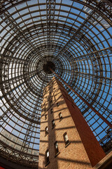 Photograph of the historic Coop's Shot Tower in Melbourne, Australia, encased under a massive modern glass dome at Melbourne Central Shopping Centre. A stunning contrast of old-world architecture 