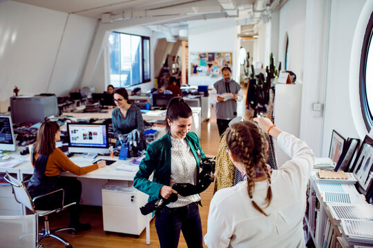 Adult women smiling over fabric selection in fashion design studio