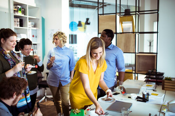 Adult coworkers smiling and celebrating with cake in modern office