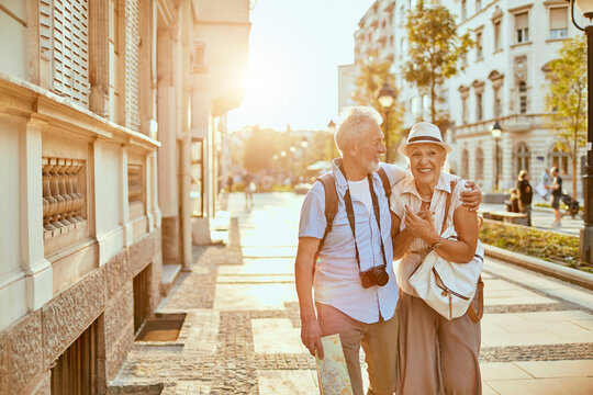 Senior couple smiling and embracing on sunny city street