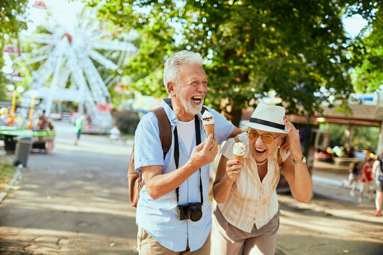 Senior couple laughing with ice cream at amusement park