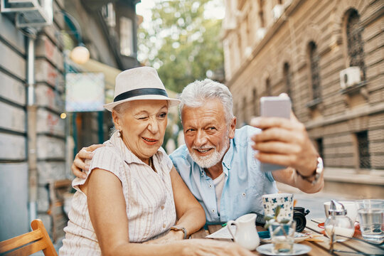 Senior couple taking playful selfie at street caf?