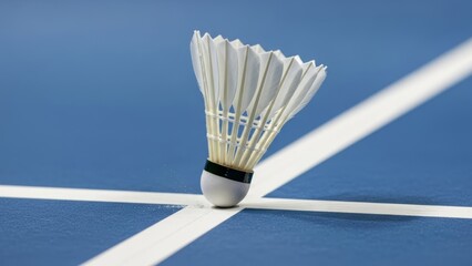 Close-up of a badminton shuttlecock precisely landing on a blue court line, showcasing perfect