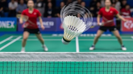 Fast-paced badminton action captured with a spinning shuttlecock just above the net during a